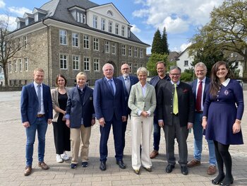 Das Bild zeigt von links Matthias Brockhagen (zukünftiger Schulleiter), Jennifer Krause (stellv. Schulleiterin), Ruth Orthaus (Vorsitzende Ausschuss für Schule, Sport, Jugend und Soziales), Bürgermeister Antonius Wiesemann, Marcus Henninger (Bauamt der Stadt Neuenrade), Dorothee Feller, Nordrhein-Westfalens Ministerin für Schule und Bildung, Heiko Zahn (Schulpflegschaftsvorsitzender), Till Hübscher (Schulrat des Märkischen Kreises), Awerd Riemenschneider (Schulleiter) und Ira Valsamidou (Schulamt der Stadt Neuenrade) vor der Burgschule Neuenrade.