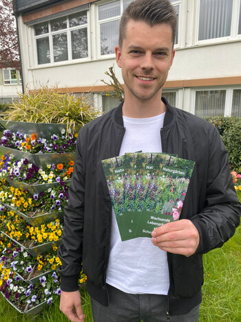 Klimamanager Simon Mai präsentiert den Naturgärten-Flyer.